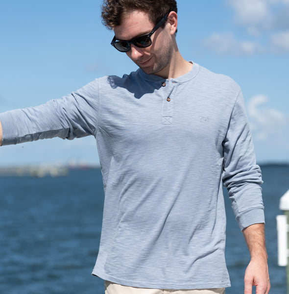 Man wearing tradewind long-sleeve shirt by the ocean